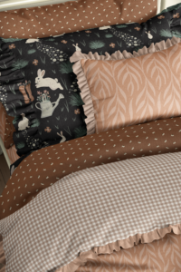 Modern bohemian kids bedding. Coral, rust, and spruce green palette with whimsical bunnies on dark background.